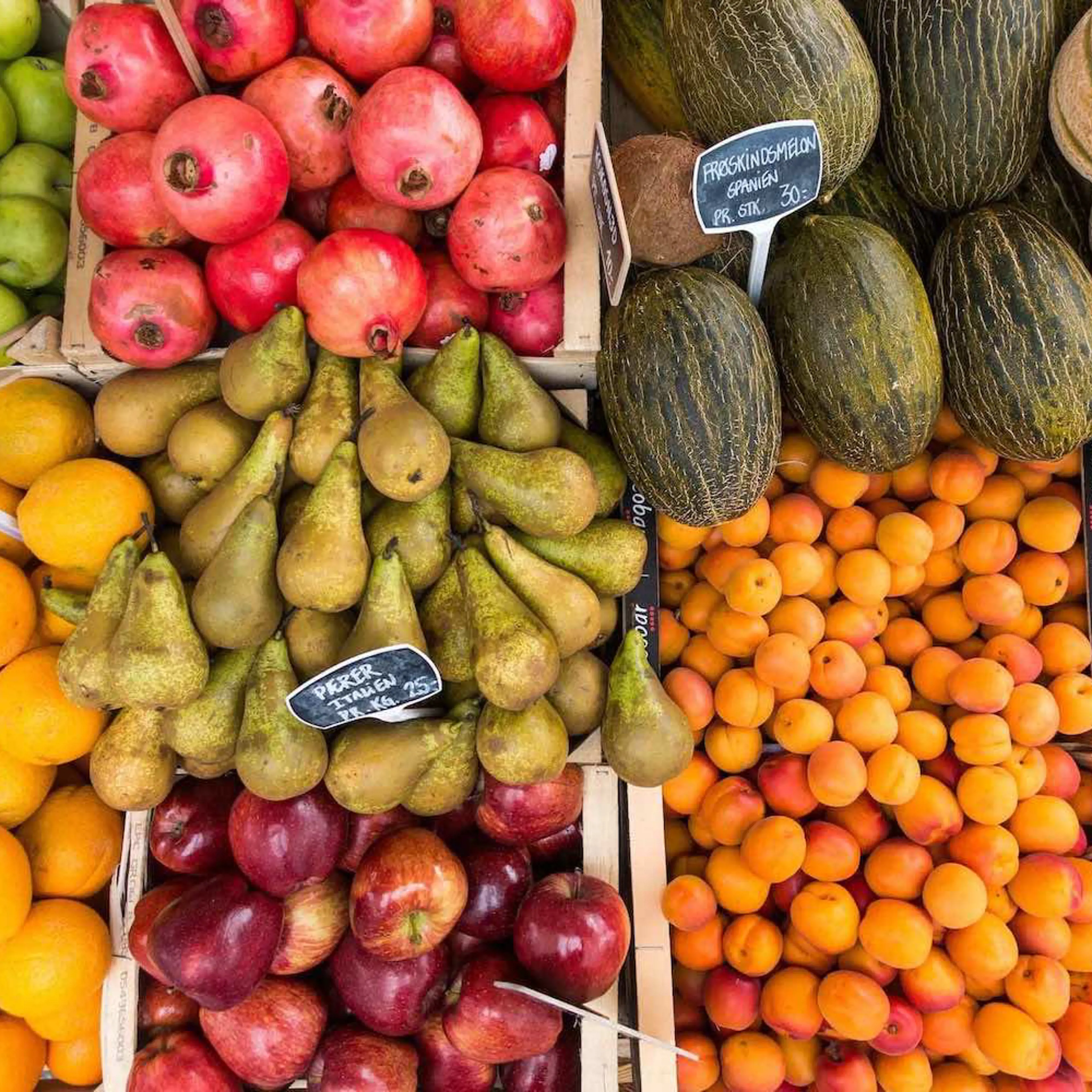 Orange, grønne og røde frugter til salg i en bods et ovenfra