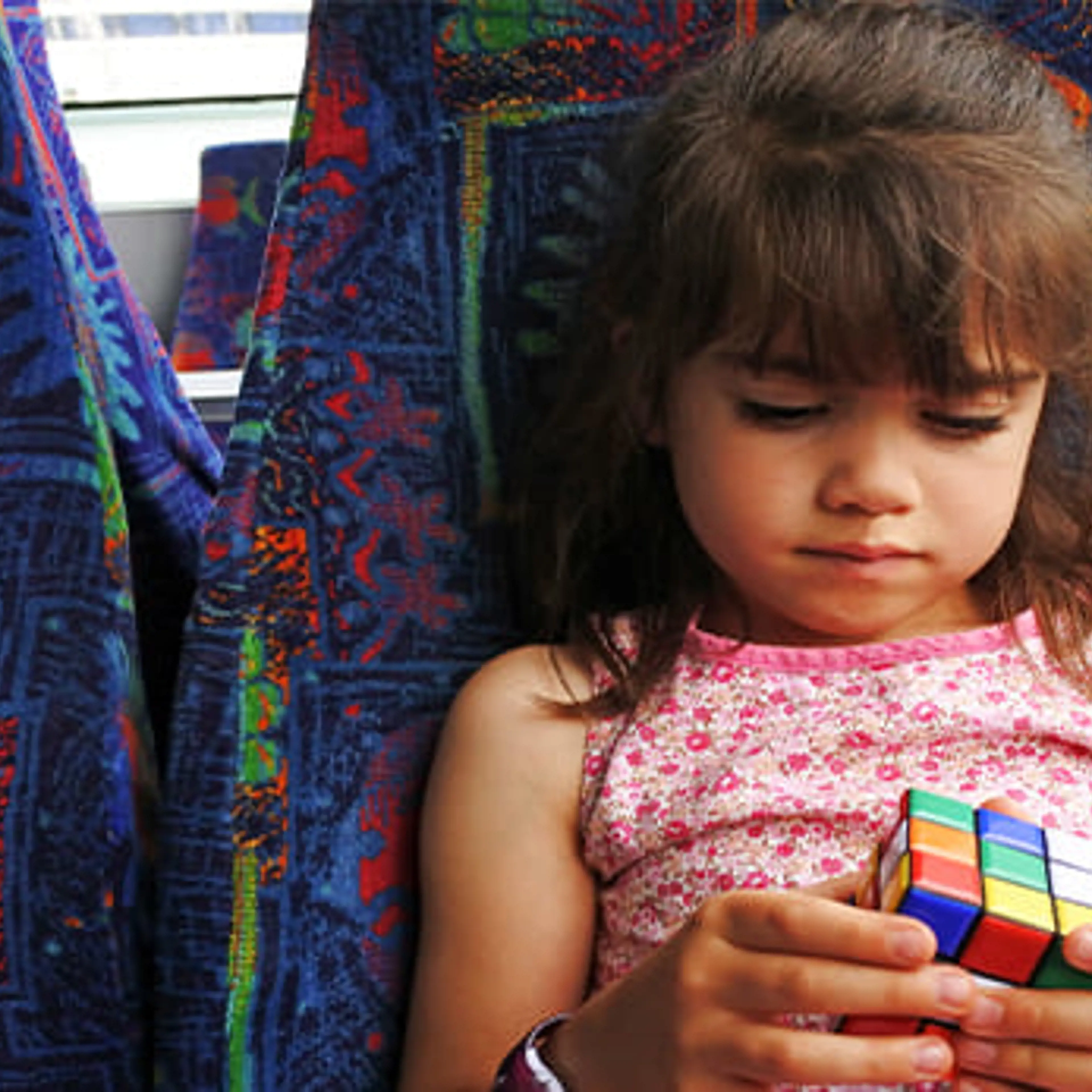 En lille pige i en bus leger med en rubiksterning