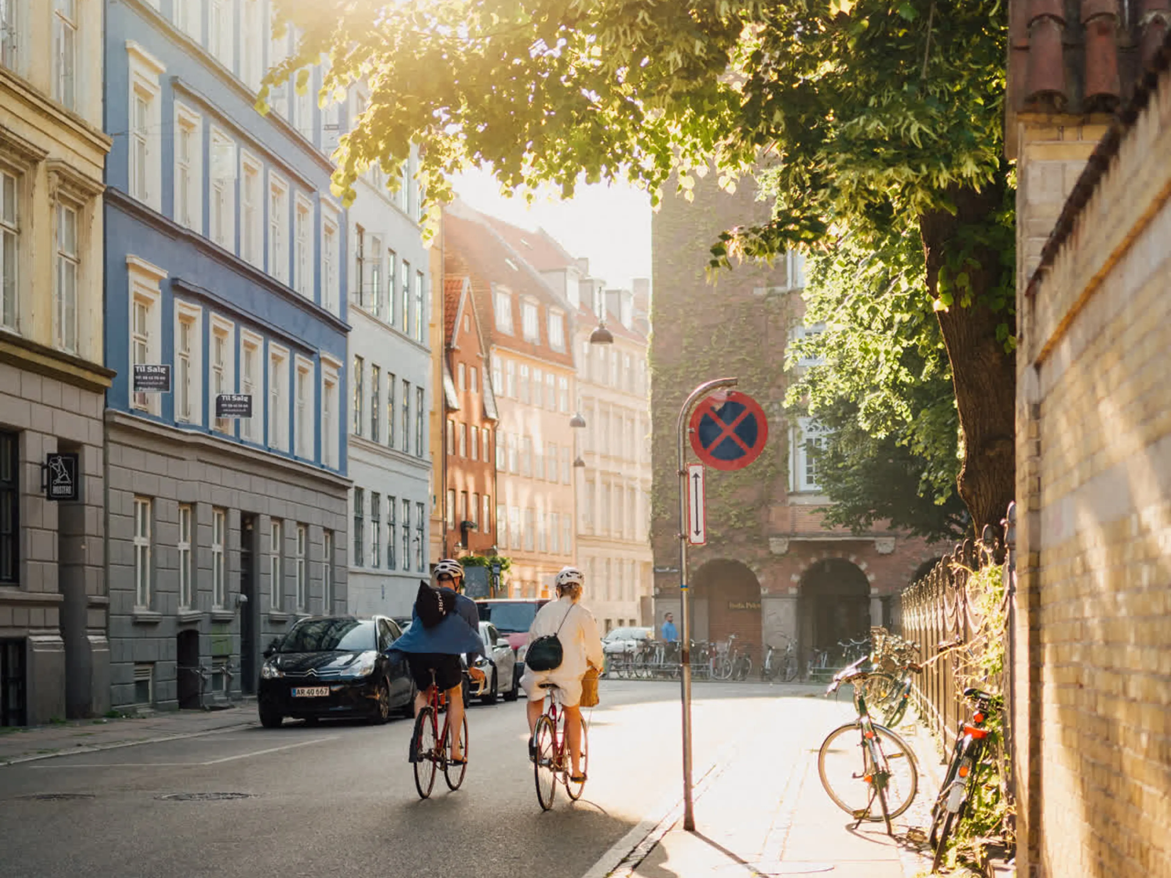 Two people biking in the inner city of Copenhagen in the sun