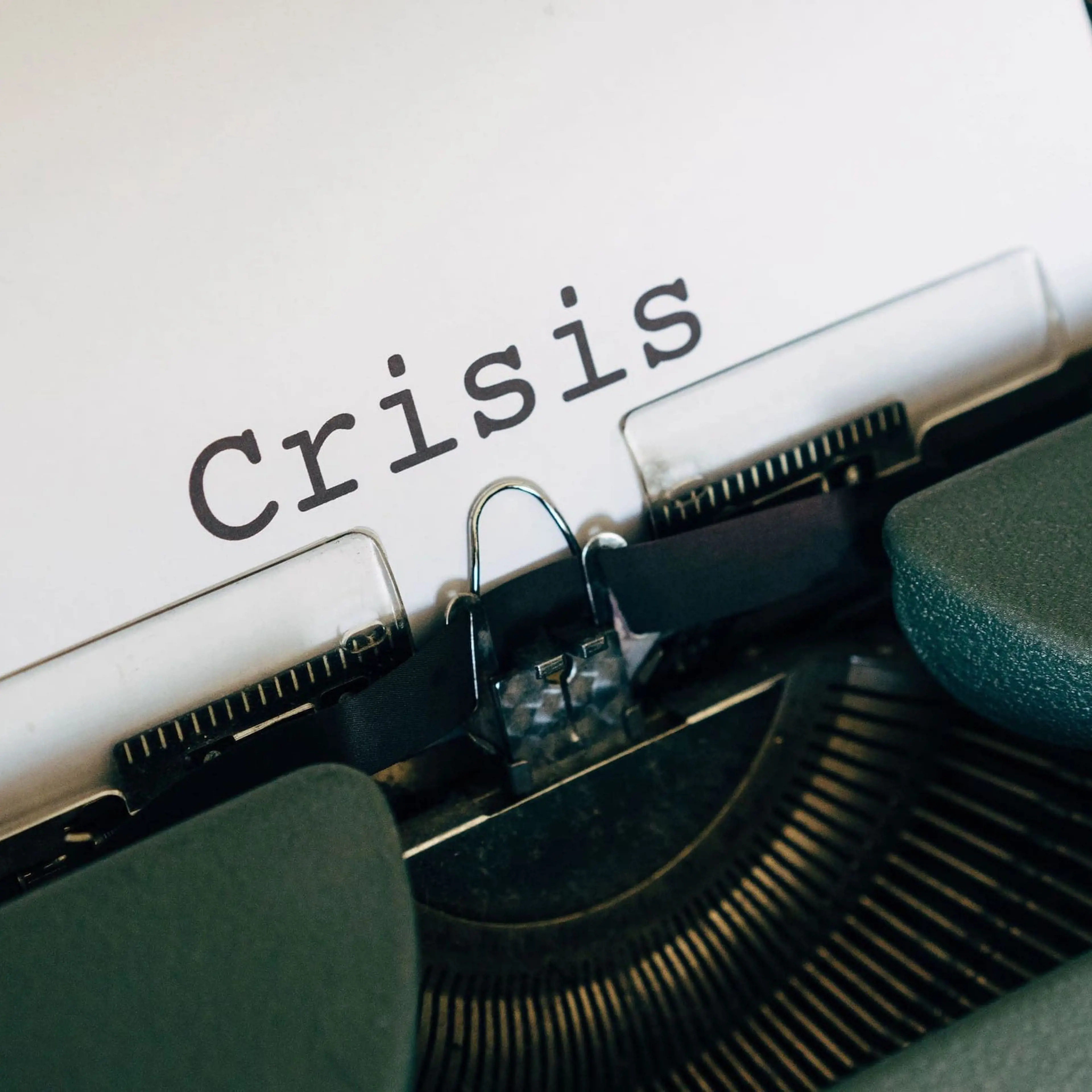 White paper sheet in a typewriter with the word "Crisis" typed in
