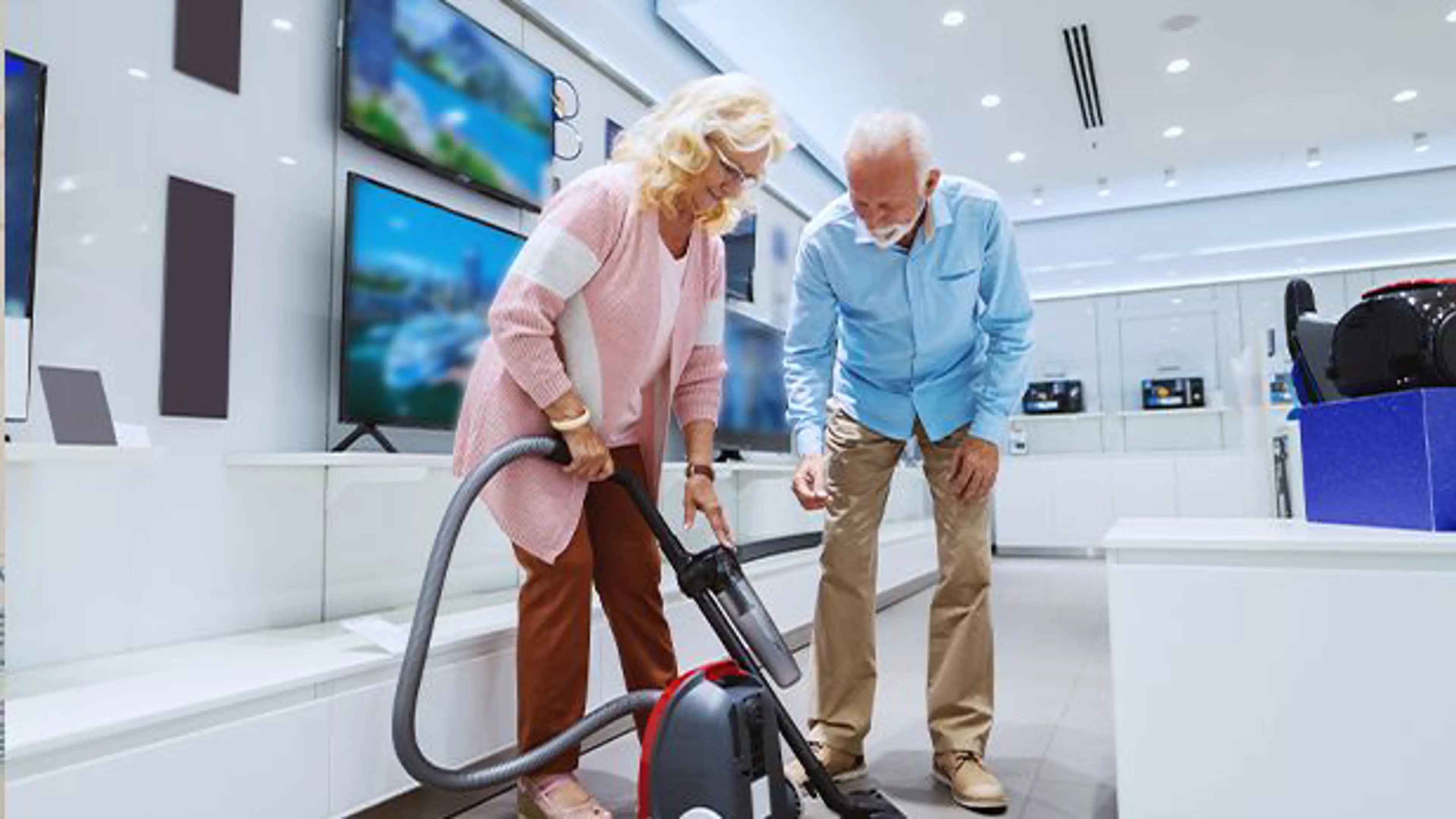 A woman and a man testing a vacuum cleaner in a store