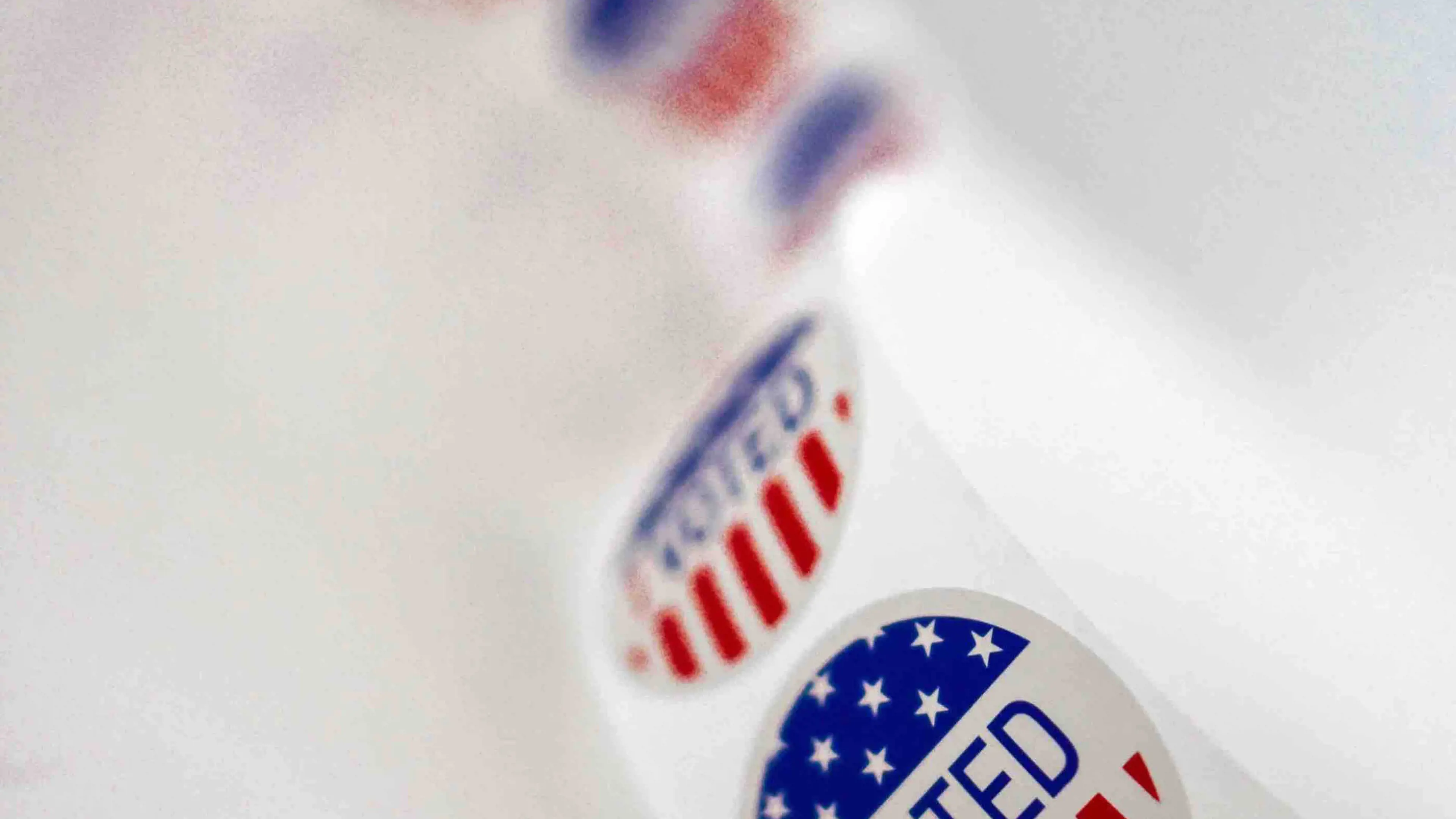 Roll of red, white and blue 'Voted' stickers on a white background
