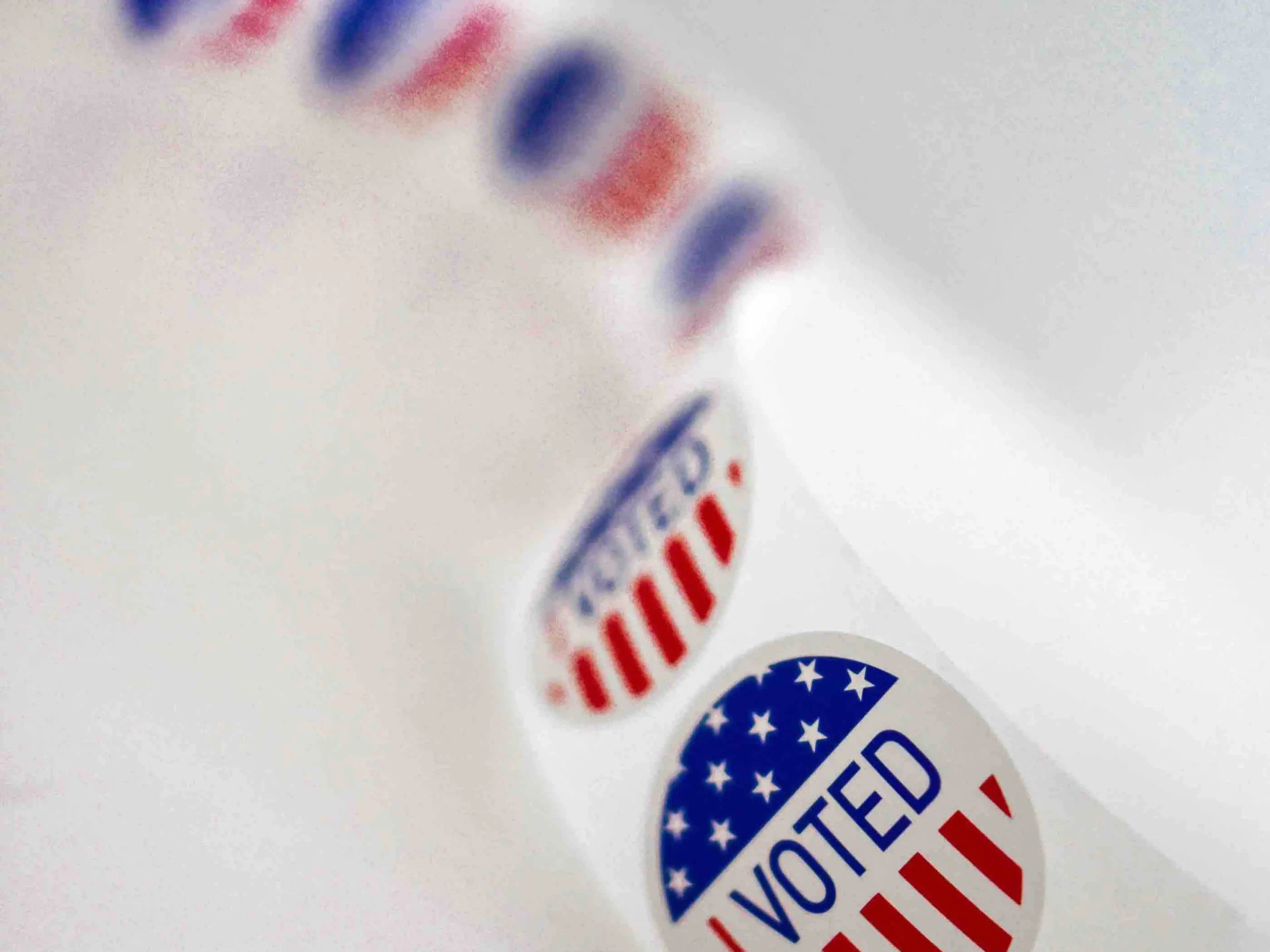 Roll of red, white and blue 'Voted' stickers on a white background